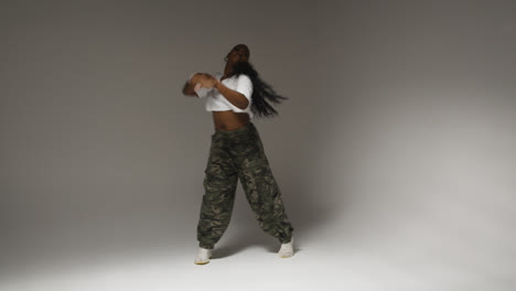 Full-Length-Studio-Portrait-Shot-Of-Young-Woman-Dancing-With-Low-Key-Lighting-Against-Grey-Background-3